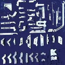 The image displays a variety of high-precision metal textile knitting machine components, such as cams, needles, and sinkers.