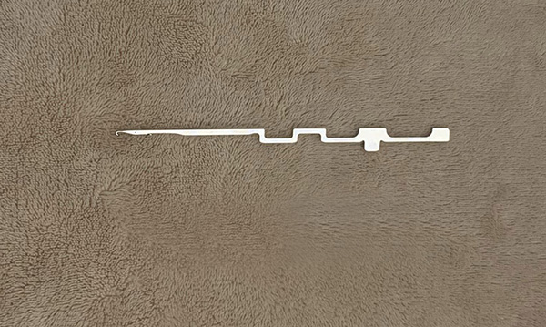 The object in the image is a steel knitting needle designed for use in industrial circular knitting machines.